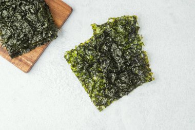 Ahşap kesme tahtasında gri arka planda kavrulmuş yosun atıştırmalığı.