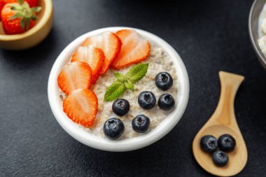 Çilekli ve yaban mersinli yulaf ezmesi kasesi. Nane arkaplanlı.