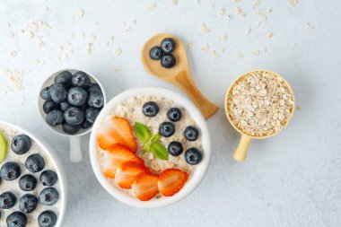 Beyaz arka planda çilekli yulaf ezmesi ve yaban mersini.