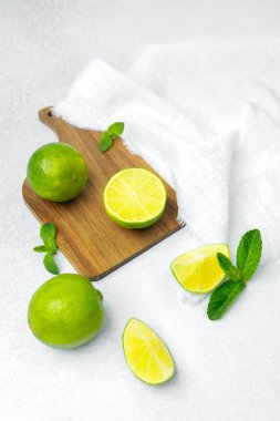 Parlak ışıkta tahta bir tahtada sergilenen sulu limon ve taze nane yaprakları..