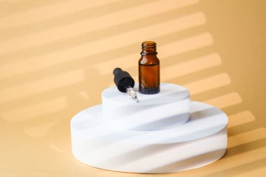 Bej üzerine kehribar camlı kozmetik serum damlası şişesi.