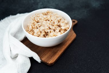 Sıcak yulaf ezmesi ahşap bir tahtanın üzerinde beyaz bir kaseye konur ve eğlenmeye hazırdır..