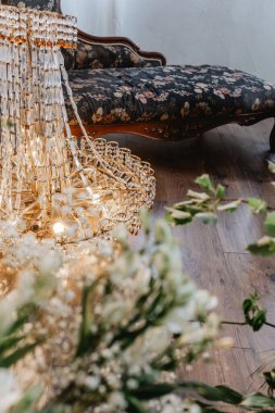 Güzel tasarlanmış bir avize, rahat bir odada çiçek aranjmanının üzerinde asılı duruyor..