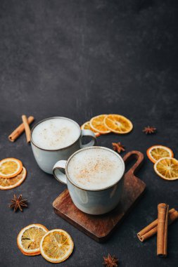 İki dumanı tüten bardak dolusu tarçınlı latte ve arka planda yıldız anason.