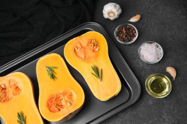 Pişirme tepsisinde biberiyeli yarım tereyağlı kabak, sarımsak, tuz, biber, yağ.