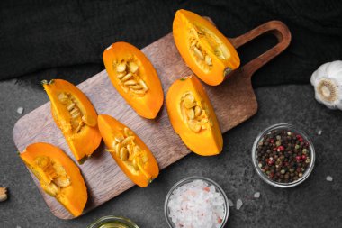 Ahşap bir tahtaya yerleştirilmiş portakal kabağı dilimleri. Biber ve tuzlu, pişirmeye hazır.