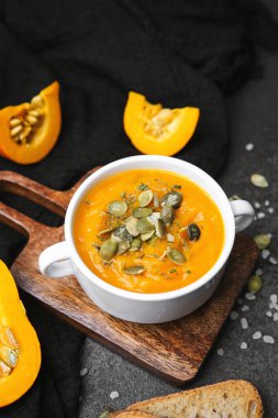 Çekirdekli portakal kabağı çorbası garnitür ve tahtanın üzerinde koyu arkaplan ile ekmek dilimi..