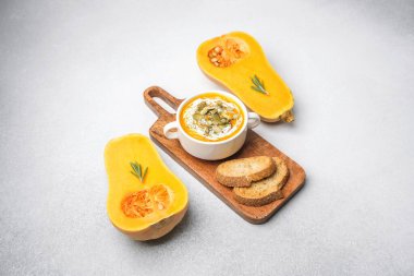 Kremalı ve tohumlu tereyağlı kabak çorbası, tahtanın üzerinde kızarmış ekmekle servis edilir..