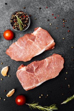 Baharatlı, kiraz domatesli ve sarımsaklı iki çiğ domuz pirzolası..