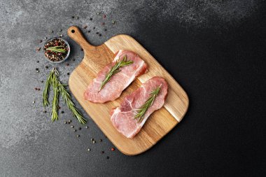 İki çiğ domuz pirzolası, taze biberiyeyle süslenmiş..