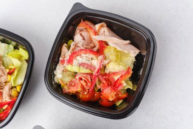 Yemek hazırlama ya da sağlıklı yemek hazırlama konsepti için içinde gurme malzemelerinin bulunduğu siyah kaplarda çeşitli taze salatalar.