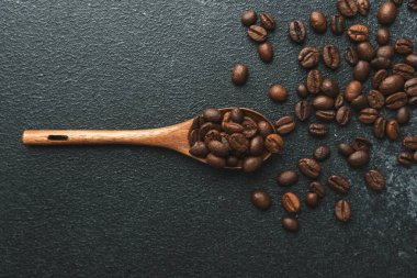 Tahta kaşıkta kahve çekirdekleri koyu arkaplanda.