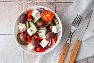 Çatal ve bıçakla fayans zemininde Yunan salatası