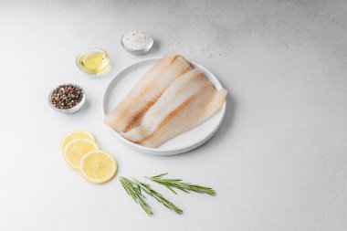 Beyaz arka planda limonlu ve biberiyeli ham pollock fileto.