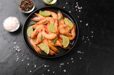 Pişirme malzemesi ya da menü tasarım konsepti için kara taş zemin üzerinde bitki ve deniz tuzu ile karides yemeği