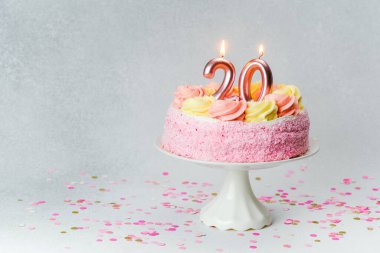 Pembe şekerli ve mumlu süslü bir pasta 20. yaş günü kutlamasıdır..