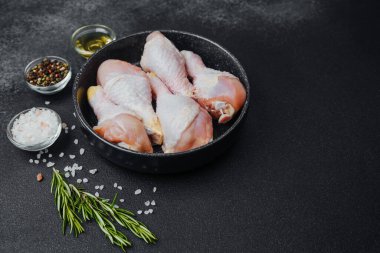 Siyah kasede çiğ tavuk budu ve baharat.