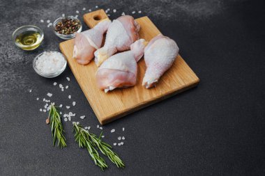 Ahşap tahtada çiğ tavuk budu ve baharat.