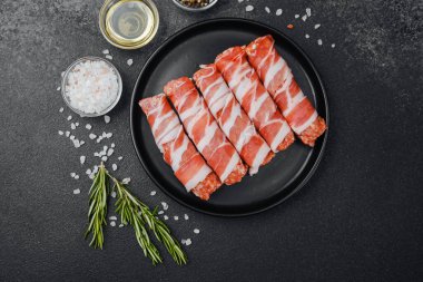 Domuz pastırmasına sarılı çiğ et ruloları ve baharatlar.