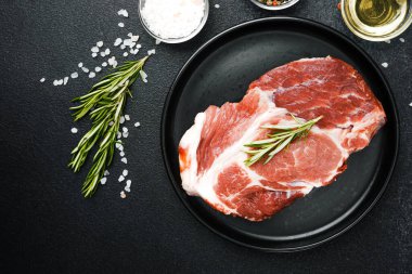 Çiğ biftek, otlar ve siyah tabakta baharatlar.