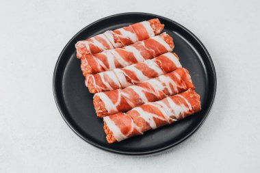 Domuz pastırması siyah tabakta baharat ve biberiye ile sarılmış.