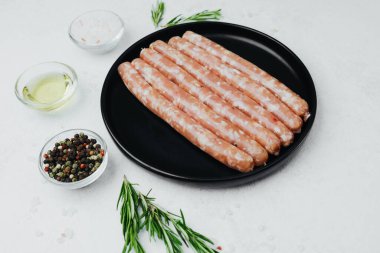 Siyah tabakta taze domuz sosisi, biberiye ve tuz.