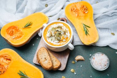 Kabak yarımları ve ekmeğin yanında çekirdekli kabak çorbası.