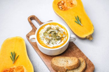 Tahta tahtada ekmek ve taze kabakla servis edilen, çekirdekli ve kremalı kabak çorbası.