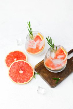 Biberiyeli greyfurt kokteyli ve narenciye dilimleri ve köpüklü sıvı içeren buz.