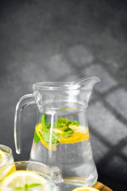 Nane yaprağı ve buz küpleriyle dolu bir sürahi limonata. Koyu yaz masasında, güneş ışığında.