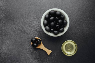 Siyah zeytinyağı ve koyu renkli zeytin yağlı arka planda.