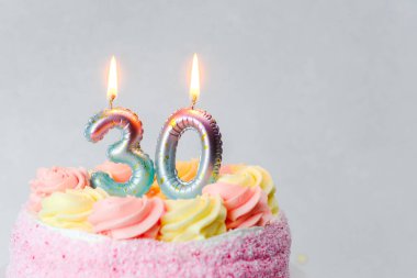 Pastel şekerli canlı bir doğum günü pastası ve 30 'luk işaretli iki mum..