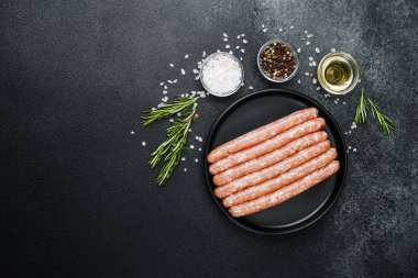 Siyah tabakta çiğ domuz sosisi ve biberiye.