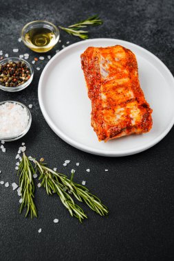 Beyaz tabakta marine edilmiş domuz pirzolası ve baharat.