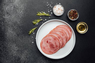 Yuvarlak dilimlenmiş sosis tabakta otlar ve baharatlar siyah masada