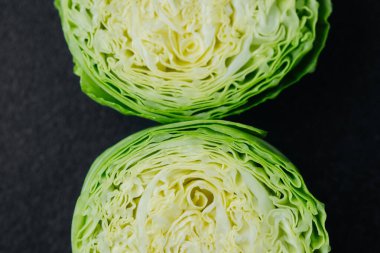 Karanlık arka planda iki kesik lahana parçası. Yakın plan.