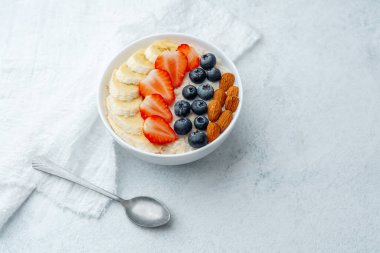 Dengeli yulaf ezmeli kahvaltı. Meyve ve badem soslu, kaşık üstüne bez.