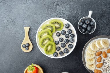 Yulaf ezmesi kasesinin üstünde kivi ve böğürtlen ve çeşitli meyveler var.