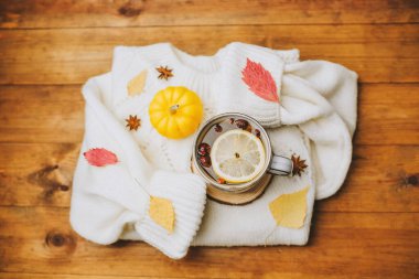 Sıcak su, limon dilimi, küçük balkabağı, yıldız anason ve sonbahar yapraklı sıcak beyaz süveter.