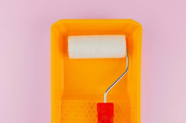 Ev boyama ve yenileme konsepti için pembe arka planda sarı tepside kırmızı saplı silindir.