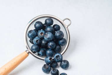 Yaban mersini arkaplanı hafif olan ince bir ağ süzgecinde yıkanır..