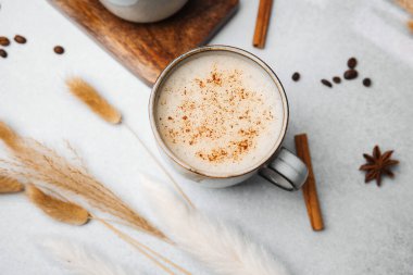 Tarçınlı bir bardakta sıcak latte ve kuru kamışlı açık bir yüzeyde yıldız anason.