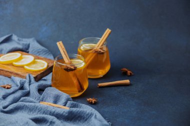 Limonlu, tarçınlı iki sıcak içecek ve koyu mavi bir masada yıldız anason.