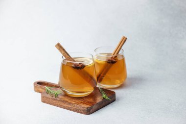 Tarçın çubuklu sıcak elma şarabı, ahşap tahtada yıldız anason ve biberiye, parlak.