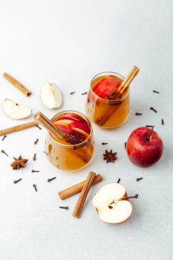 Tarçın çubuklu sıcak elma şarabı, yıldız anason ve açık arkaplanda karanfiller.