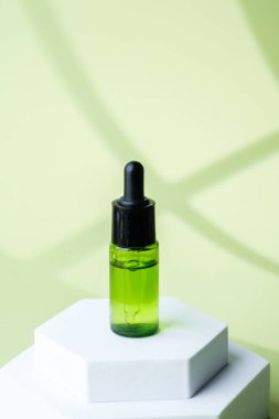 Siyah kapaklı yeşil cam kozmetik damlası şişesi.