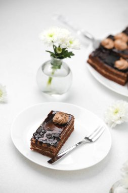 Çatallı ve beyaz çiçekli zengin çikolatalı pasta dilimi..