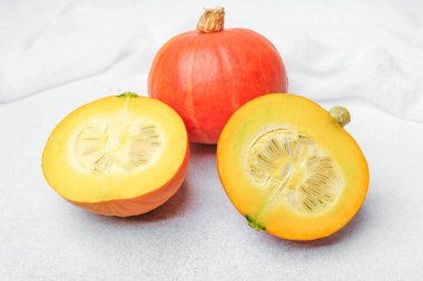 Tohumları gösteren turuncu balkabağı ve beyaz kumaş arka planda gövde