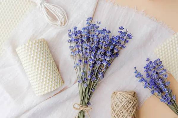 Lavanta buketi, balmumu mumları ve şeftali rengi kumaş arkaplan malzemeleri.