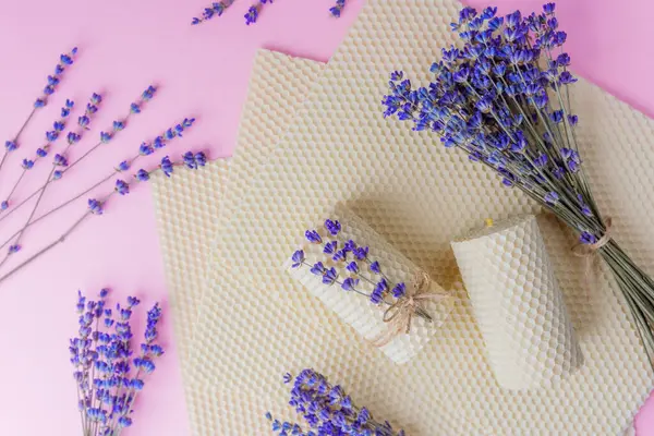 Balmumu mumlar ve pembe arka planda lavanta demetleri